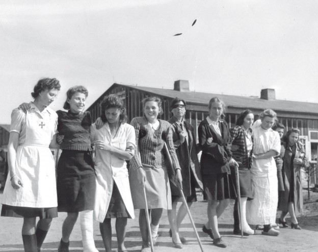 „Lazarettpatientinnen werden auf einen Spaziergang geführt. Viele der Frauen leiden noch an Kriegsverletzungen.“ (Originalbeschriftung, Übersetzung aus dem Englischen). Foto vom 7. Mai 1945, Fotograf: Lieutenant B.J. Gloster (Library and Archives Canada, PA 159547)